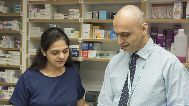 two people in community pharmacy looking at a binder