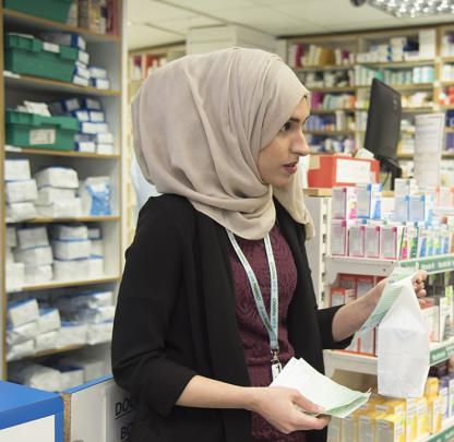 pharmacist in pharmacy premises holding a bag of medicines